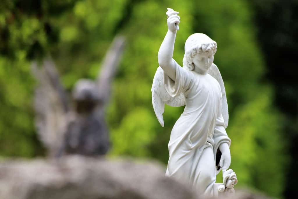 A small marble angel statue in on a grave yard representing life after death