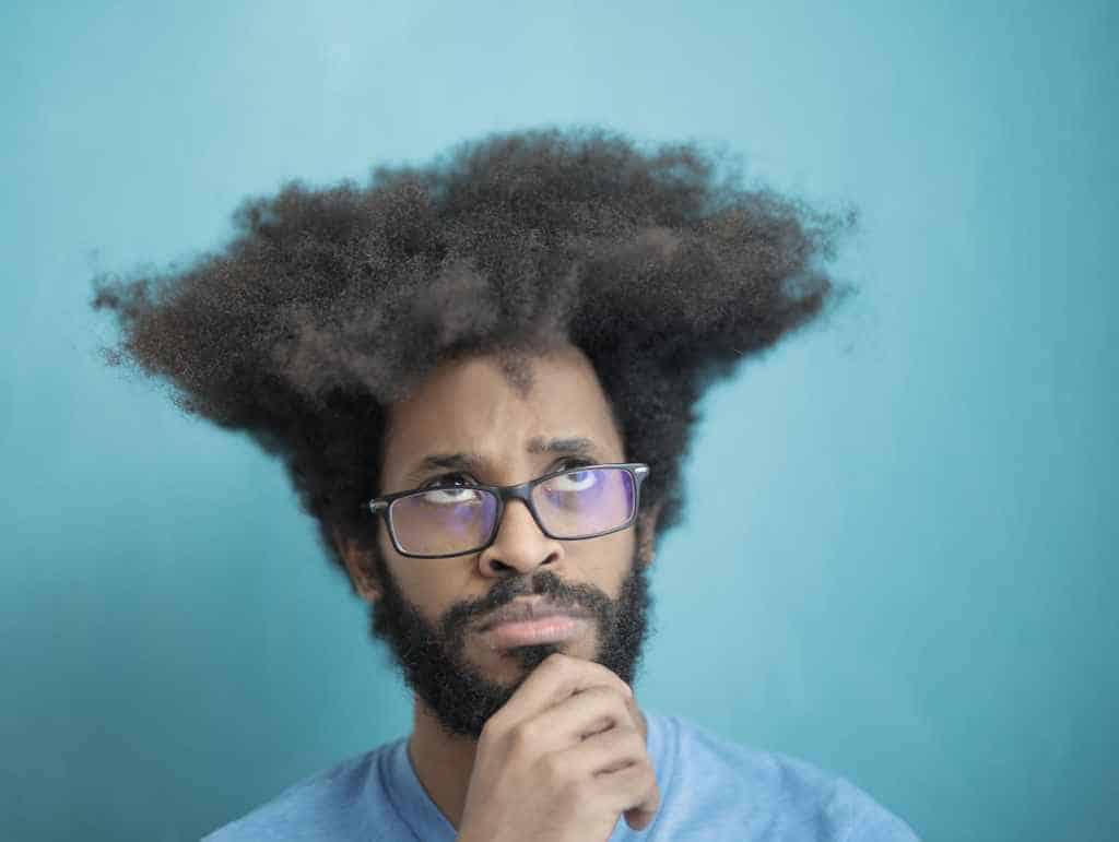 Cool young bearded man with big afro hairstyle is wondering and thinking