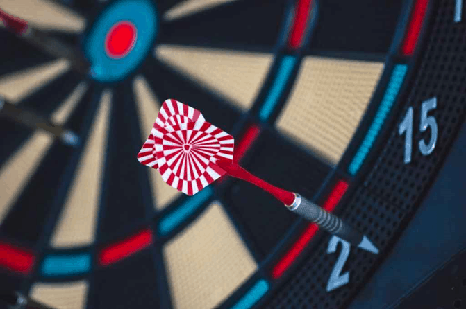 A dart lacking focus and missing the target hitting the sides of a dartboard
