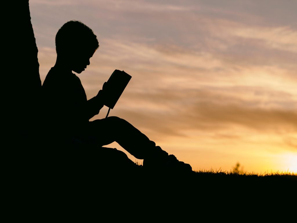 A child reading during sunset, symbolizing his positive and negative potential