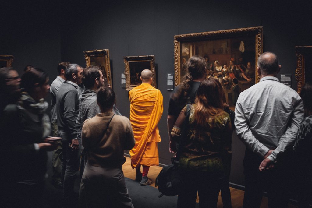 Buddhist monk admiring a painting in a modern art museum