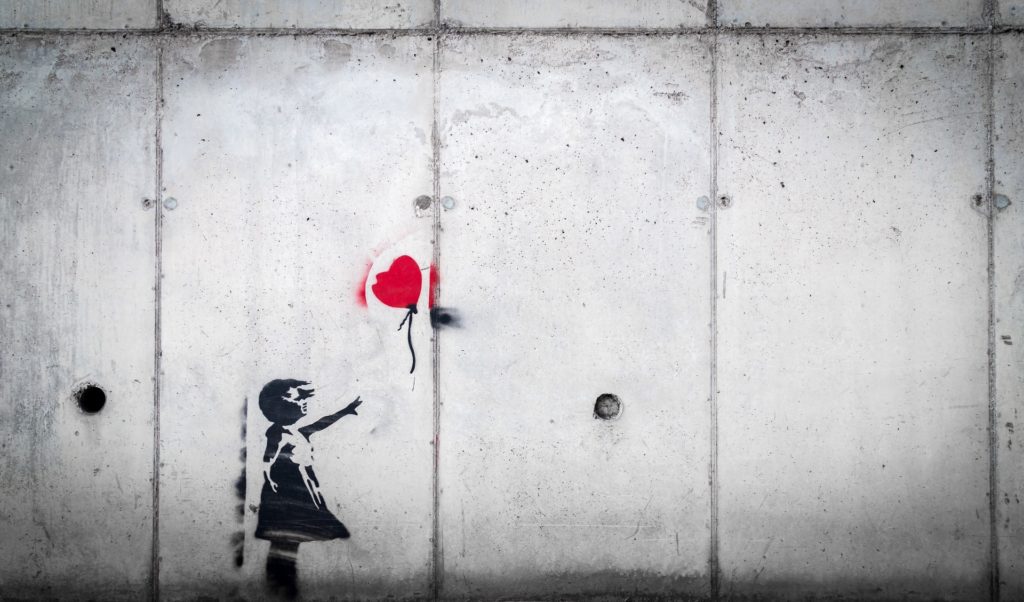 A little girl graffiti loosing her balloon that is flying away towards freedom