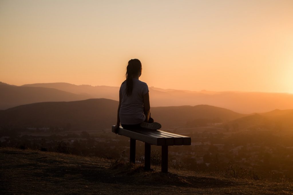 A woman meditating in the sunset listening to her inner voice